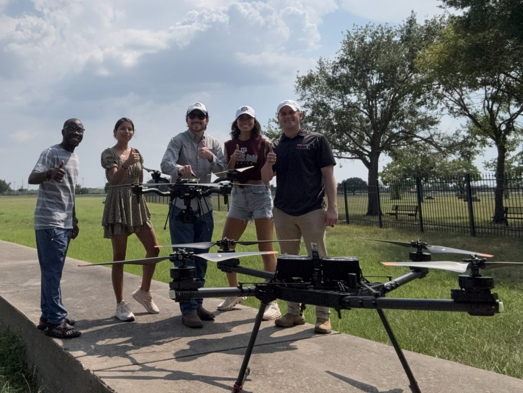 Students outside standing next to a large black drone.
